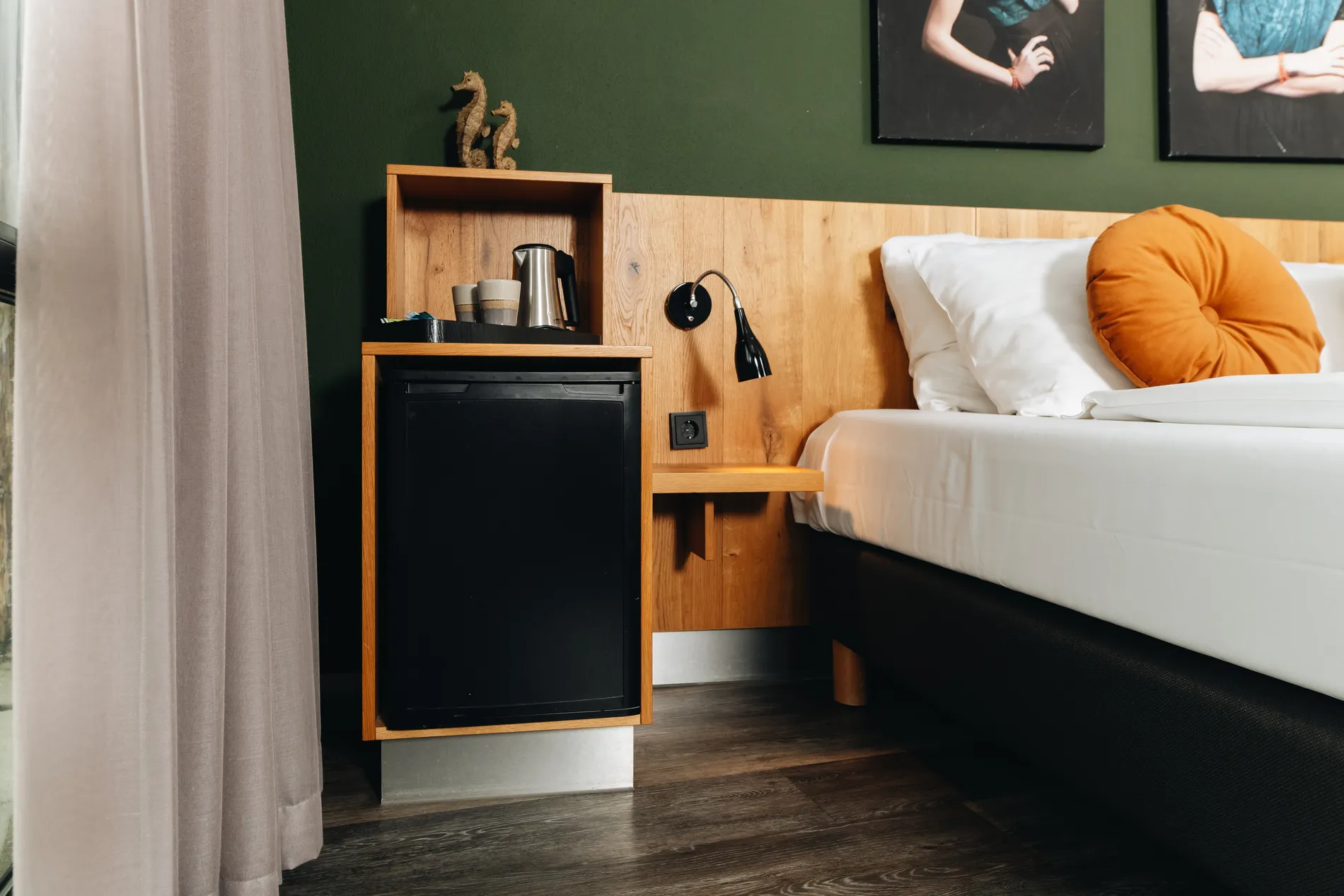 Detail van de kamerfaciliteiten met een zwarte minibar en koffiehoekje, strak geïntegreerd in het houten interieur van de hotelkamer.